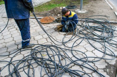 Çalışan kurulumcular kabloyu yeraltından çekiyor..