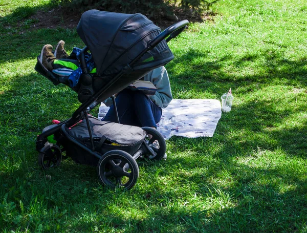 Een Vrouw Met Een Kind Een Kinderwagen Het Park Leest — Stockfoto