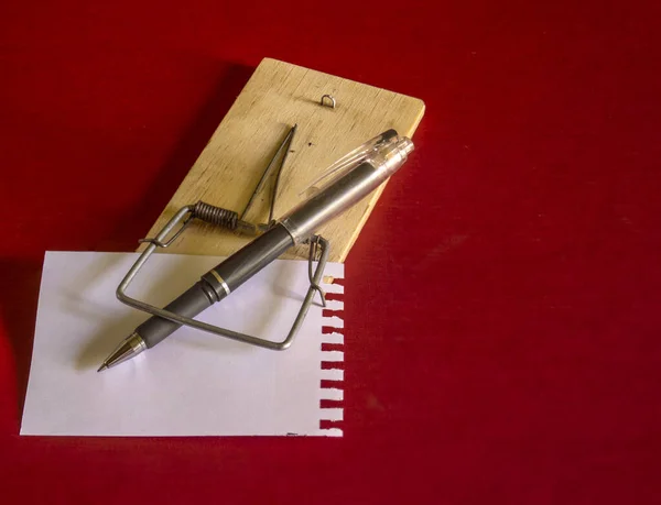 A fountain pen and a sheet of writing paper for notes on a mousetrap.