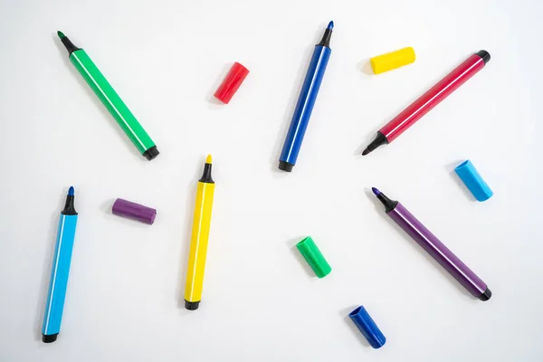 Colorful marker pens with caps removed on a white background. Close-up photo