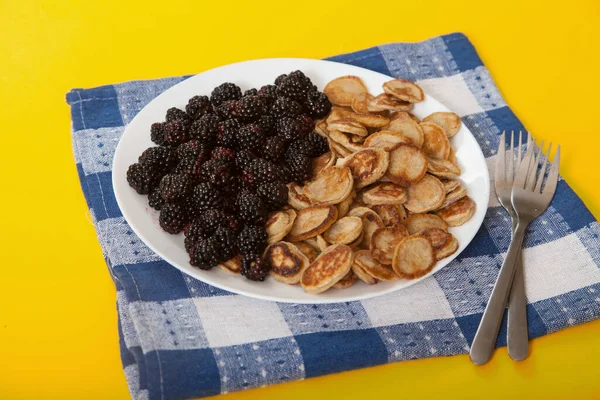 小煎饼 带着黑莓 两个叉子 蓝色餐巾 黄色背景 — 图库照片
