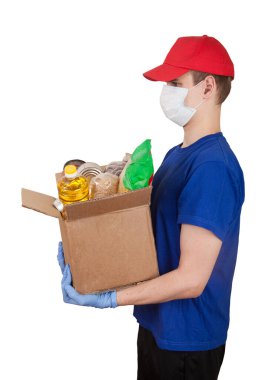 Kırmızı şapkalı genç bir gönüllü beyaz arka planda bir kutu erzak tutuyor. Sosyal konsept. Fakirlere yardım. Mal teslimatı