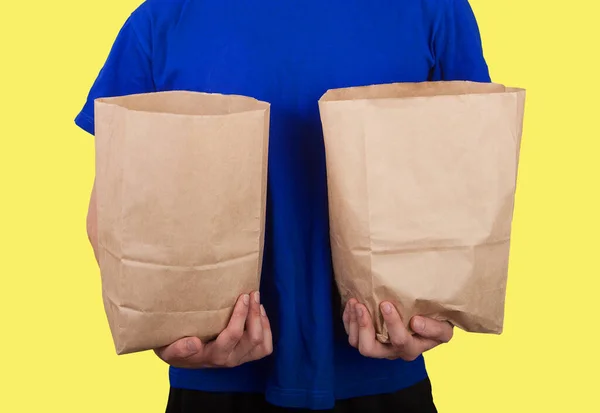 Mężczyzna Niebieskim Shircie Trzyma Dwie Papierowe Torby Zakupami Żółtym Tle — Zdjęcie stockowe