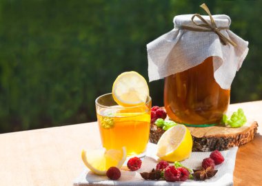 Fermente edilmiş kombu çayı kavanozda ve limon dilimleri ve ahududu dolu bir bardak ağaçtan yapılmış bir masada duruyor. Sağlıklı gıda konsepti. Kürekleri kopyala. Yatay.