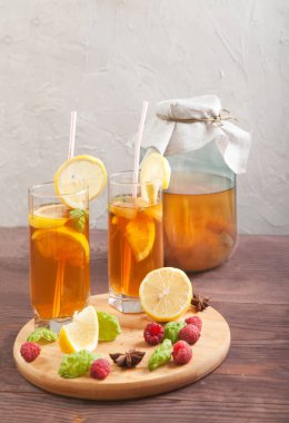 İki bardak ve kombu çayı, limon dilimleri ve ahududu ile ahşap bir masa. Kürekleri kopyala. Dikey.