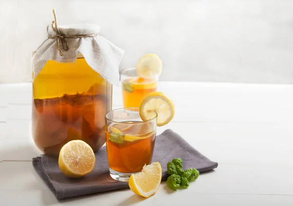 Two glasses and bank with kombucha and lemon slices on a white table. Copy spaec. — Stock Photo, Image