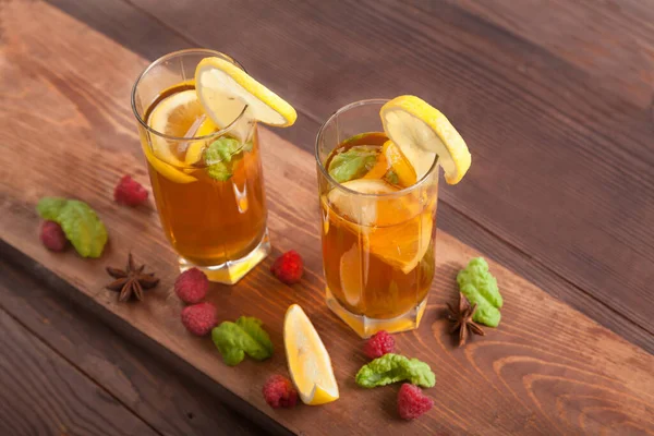 Two glasses with kombucha, drinking straws and lemon slices, raspberries are on a wooden table. Healthy food concept. — Stock Photo, Image