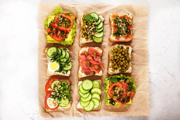 Verschiedene Sandwiches Mit Frischkäse Lachs Kräutern Und Gemüse Auf Bastelpapier Stockbild
