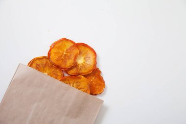 Beyaz arka planda bir torba el işi kağıdının içindeki hurma parçaları. Sağlıklı gıda konsepti. Boşluğu kopyala