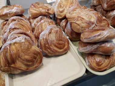 Taze pişmiş, şekerli, naylona sarılı güzel çörekler, bir mağazanın rafında uzanıyorlar. Mobil fotoğraf.