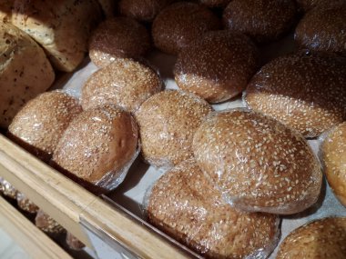 Naylon ambalaja sarılmış susamlı çörekler bir fırının rafında duruyor. Mobil fotoğraf.