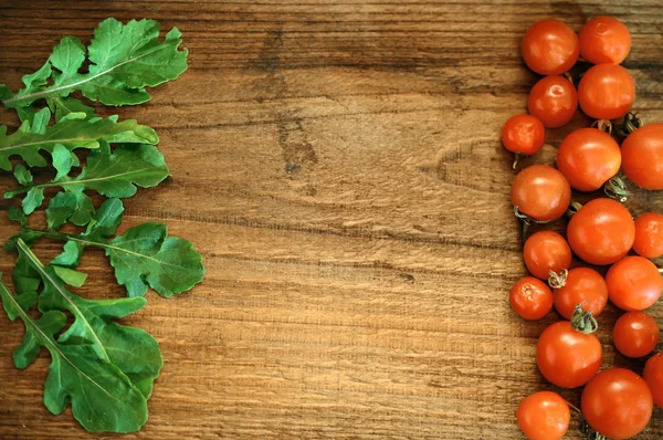 Pomodori e rucola su fondo di legno — Foto Stock