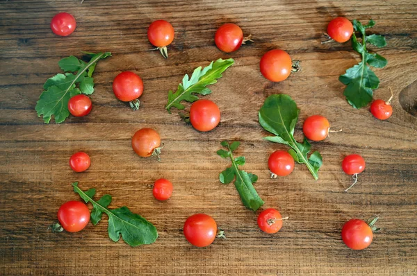Tomaten und Rucola auf einem hölzernen Hintergrund — Stockfoto