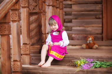 Petite Russian beauty sits on a wooden porch clipart