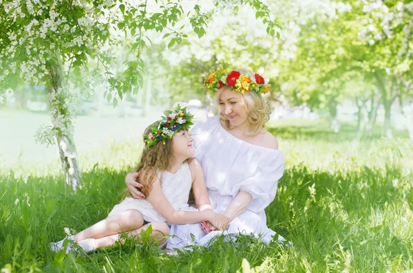 Mamá y su hija en guirnaldas florales se miran — Foto de Stock