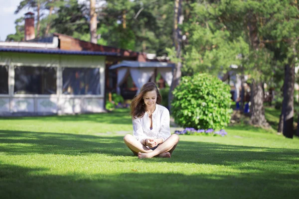 Usmívající se dívka na trávníku v lotosové pozici — Stock fotografie