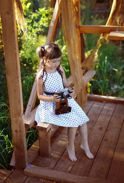 Girl sitting on the terrace and watching a film camera — Stock Photo, Image