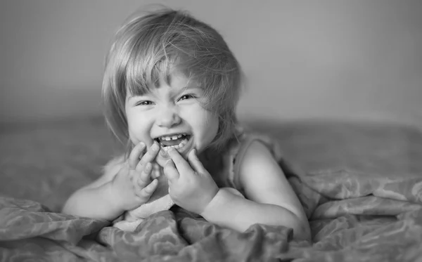 Laughing baby is lying on the bed — Stock Photo, Image