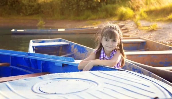 Smiling girl sitting in a boat at sunset — Stock Photo, Image