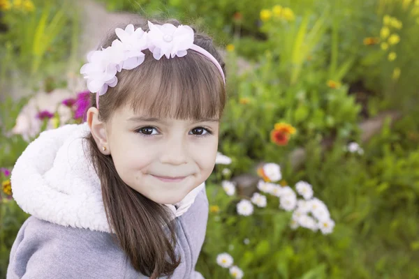 Portrait of a smiling girl on the background of greenery and flowers — Stock Photo, Image