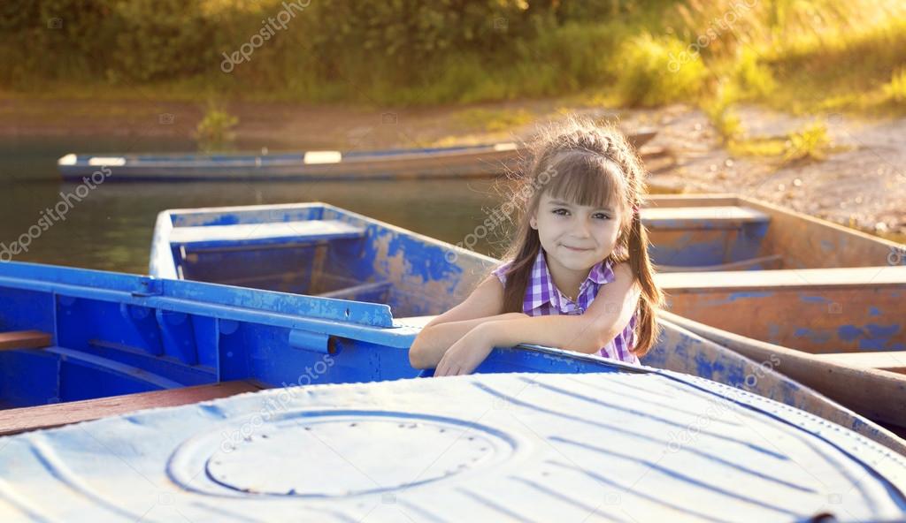 Smiling girl sitting in a boat at sunset