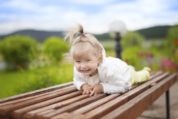 Smiling girl lying on the bench — Stock Photo, Image