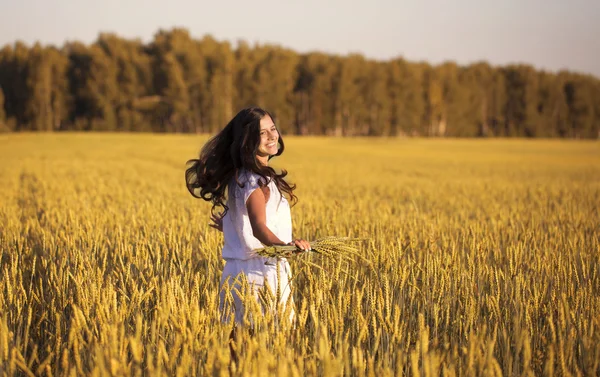 Улыбающаяся красивая девушка крутится в поле из пшеницы с ушами — стоковое фото