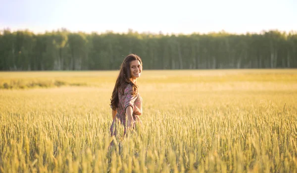 Sonriente hermosa chica entre las espigas de trigo dorado — Foto de Stock