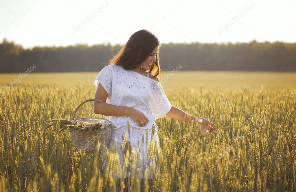 Beautiful girl standing in field with basket of corn