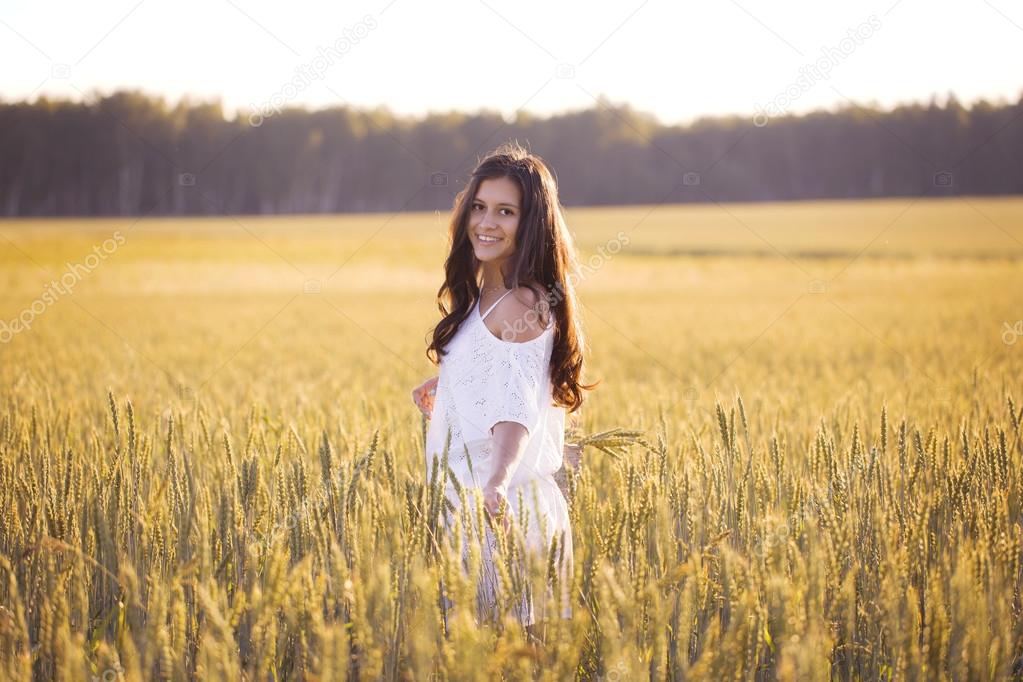 Smiling beautiful girl in wheat field turned