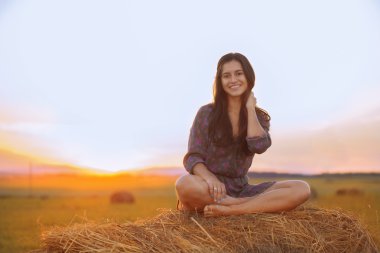 Smiling girl sitting in the Lotus position at sunset