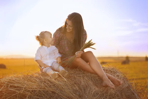 Una giovane donna con un bambino nel fieno nel campo — Foto Stock