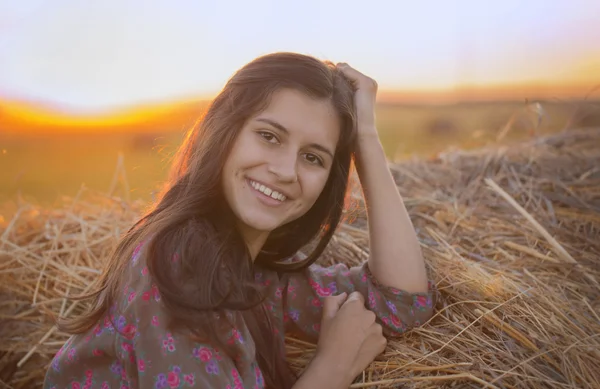 Sonriendo hermosa chica se apoyaba en el pajar — Foto de Stock