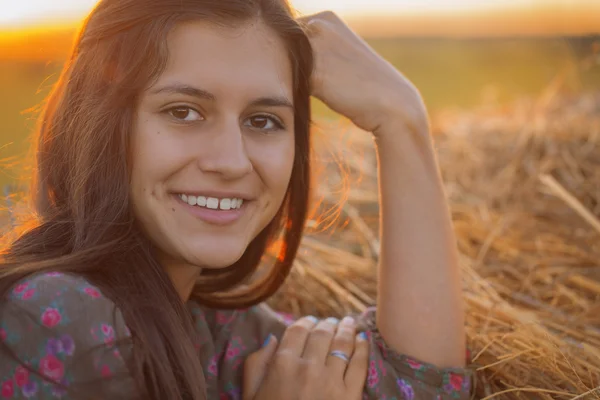 Retrato de una chica sonriente al atardecer en un pajar —  Fotos de Stock