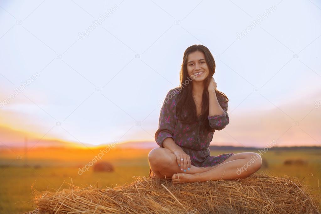Smiling girl sitting in the Lotus position at sunset