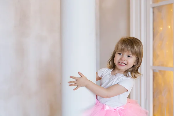 Smiling girl peeks out and holds the column — Stock Photo, Image