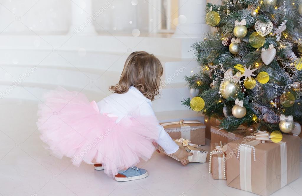 Elegant girl takes a gift under the Christmas tree