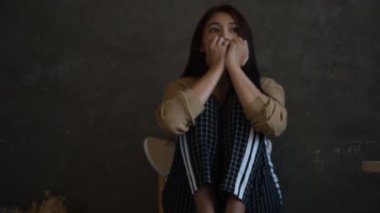 Stresli bir kadının elini kaldırdığı yavaş bir görüntü. Denenmiş ve üzgün bir şekilde, ahşap taburede oturan negatif bir duyguyla kafasına dokunuyor.