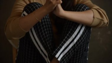 Stresli bir kadının elini kaldırdığı yavaş bir görüntü. Denenmiş ve üzgün bir şekilde, ahşap taburede oturan negatif bir duyguyla kafasına dokunuyor.
