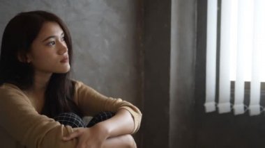 Stresli bir kadının elini kaldırdığı yavaş bir görüntü. Denenmiş ve üzgün bir şekilde, ahşap taburede oturan negatif bir duyguyla kafasına dokunuyor.