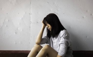 Mutsuz kadın elini başına koydu, üzgün ve üzgün bir şekilde, bulanık bir ışıkla.