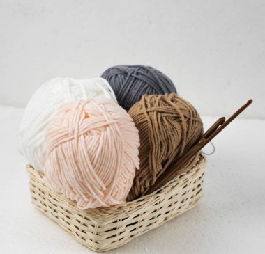 İplik topları ve ahşap örgü kancaları örülmüş sepet, bulanık aydınlatma.