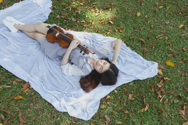 바이올린과 보손을 공원에서 느끼며 바닥에 아름다운 아가씨 — 스톡 사진
