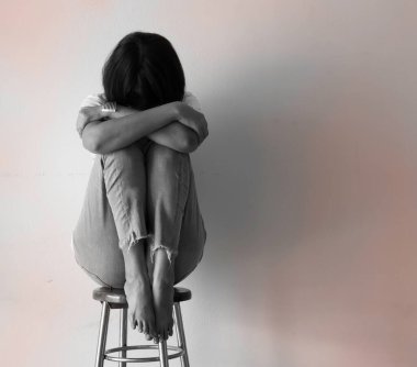 Woman sit and hug her knees up on the chest,turn face down,panic and upset feeling,mental.black and white tone,blurry light around