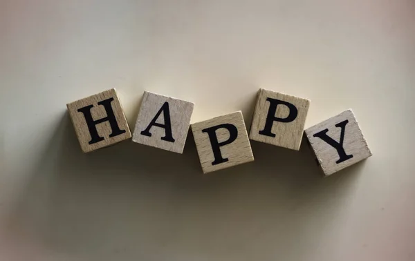 HAPPY word written on wood block,on background,vintage and art tone,blurry light around