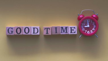 İyi TIME kelimesi ahşap blok ve kırmızı alarm saati .vintage ve sanat tonu, etrafında bulanık ışık