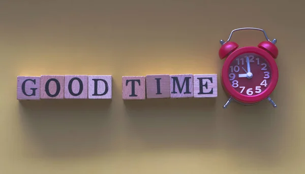 GOOD TIME word written on wood block and red alarm clock .vintage and art tone,blurry light around