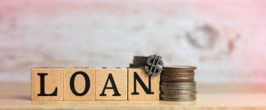 LOAN word written on wood block and coins put on timber board,blurry light around