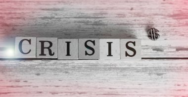 CRISIS word written on wood block put on timber board,blurry light around,Lens flare effect