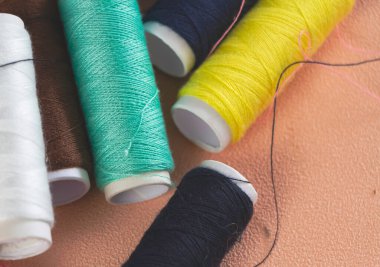 Sarı ve bulanık beyaz rulonun ortasına konan yakın yeşil iplik, pastel arka planda